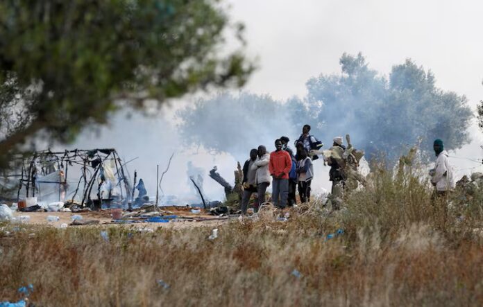 Migrants gather near burnt tents, as Tunisian authorities have dismantled makeshift camps housing sub-Saharan African migrants, in Amra, Sfax, Tunisia April 24, 2025. REUTERS/Zoubeir Souissi